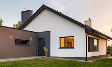 Panorama of a stylish house with large lawn and garage, outdoors